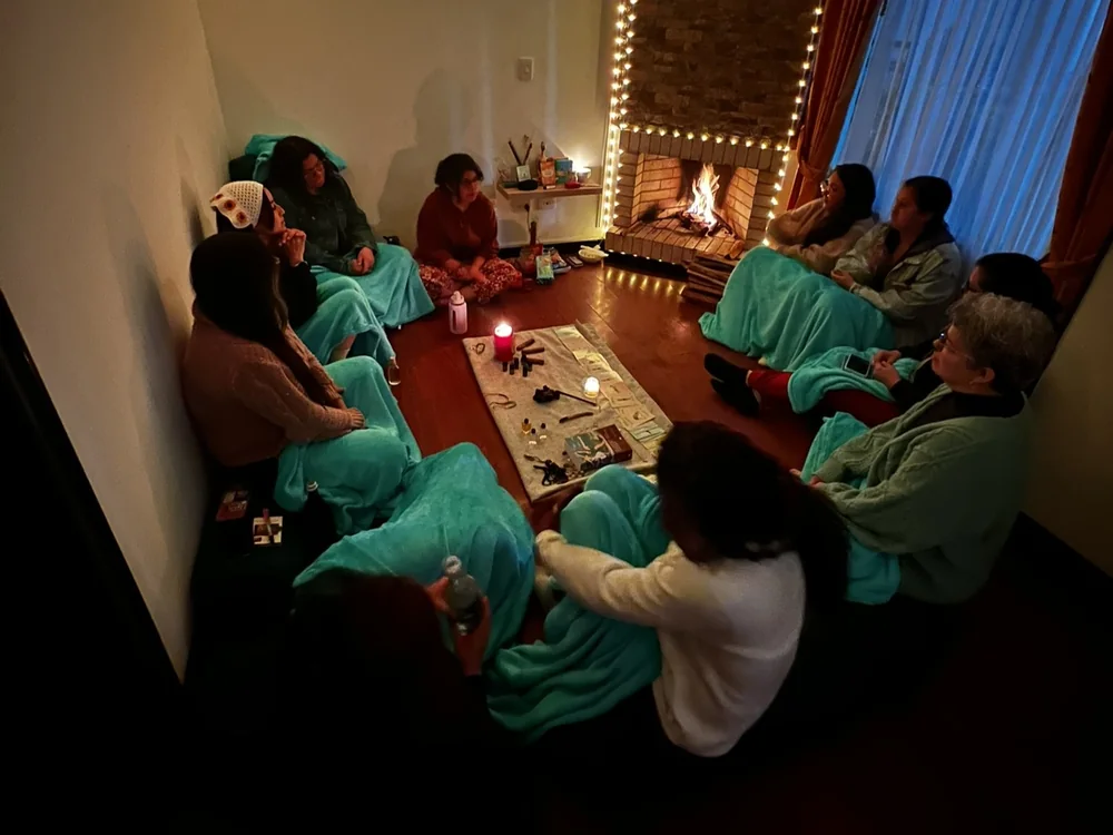 Mujeres comparten en un círculo de palabra junto a la chimenea encendida