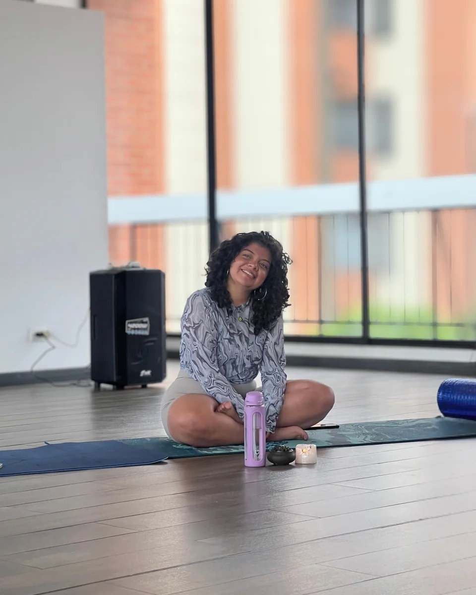 Gaby sonríe sentada sobre una colchoneta en la sala de práctica
