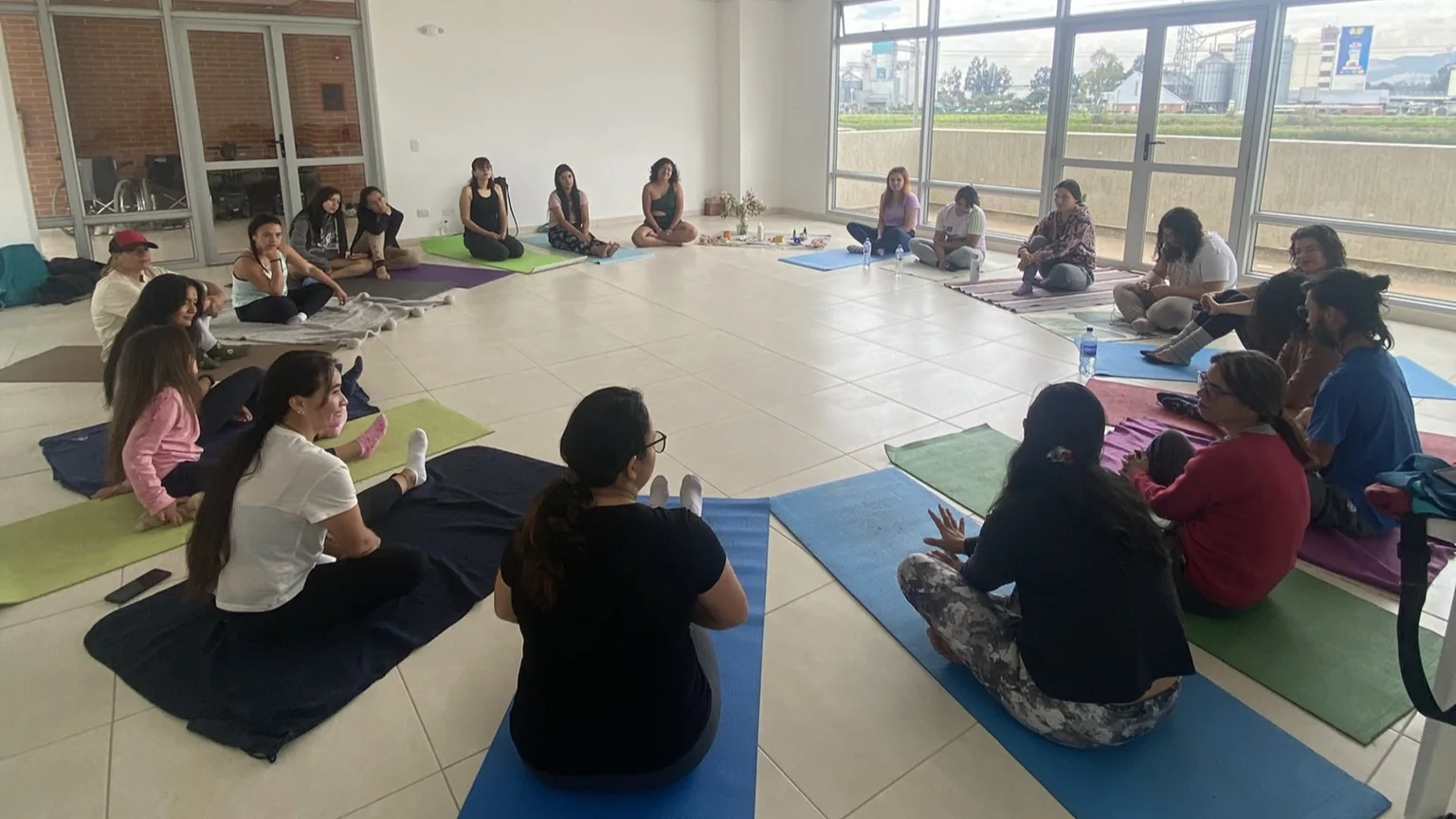 Un grupo medita sentado en círculo, con colchonetas alrededor de la sala