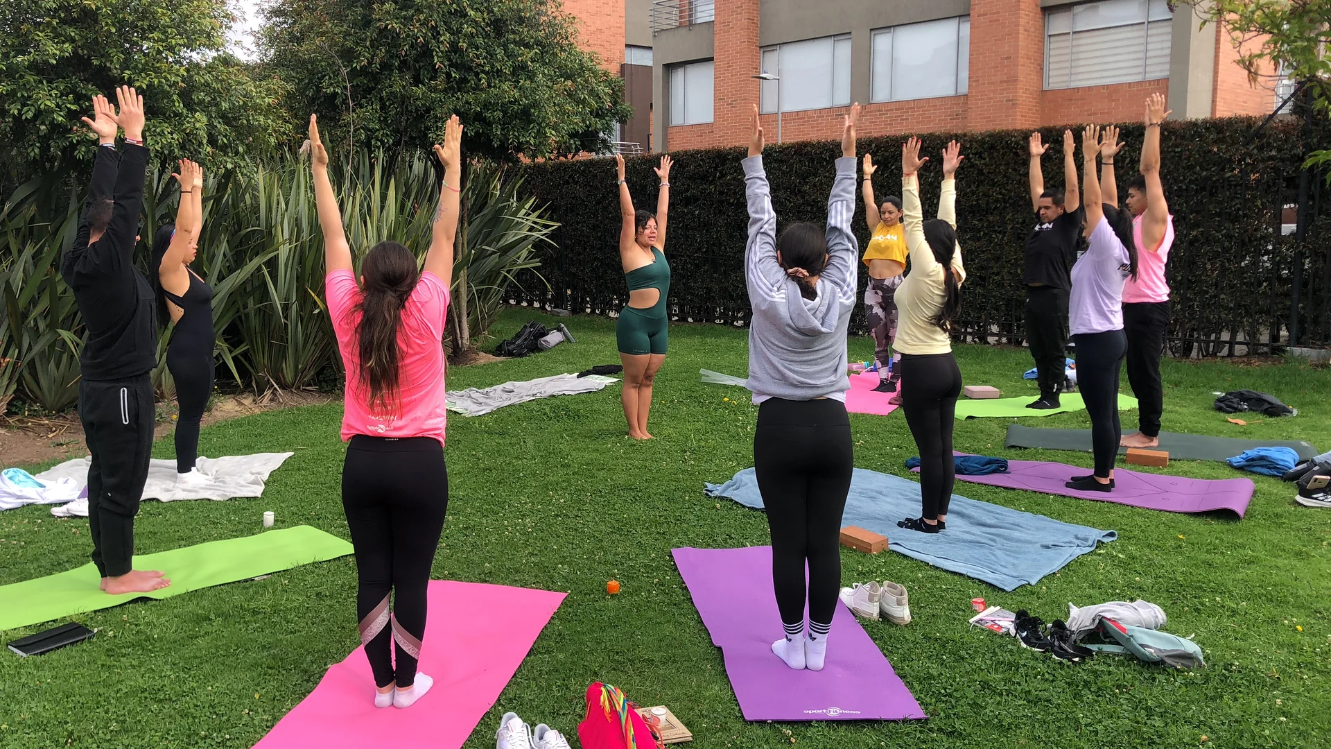 La comunidad practica yoga al aire libre, de pie con los brazos levantados